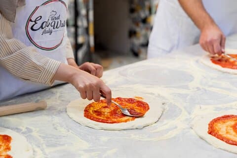 Spreading tomato sauce on pizza dough.
