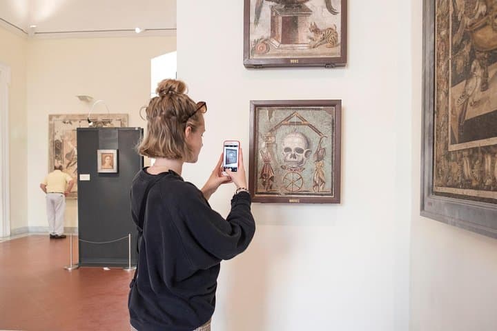 A tourist captured by a painting of "Memento Mori" at the National Archeological Museum of Naples.