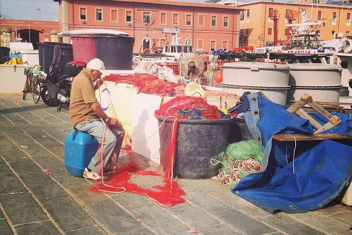 The old harbour: a fisherman working on his net