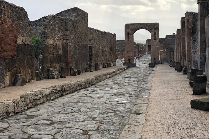A road in Pompeii -The slabs are made of basalt (volcanic stone). Please focus your attention on the roadway. Most of them in Pompeii had a donkey back silhouette to help the flowing of dirty water...