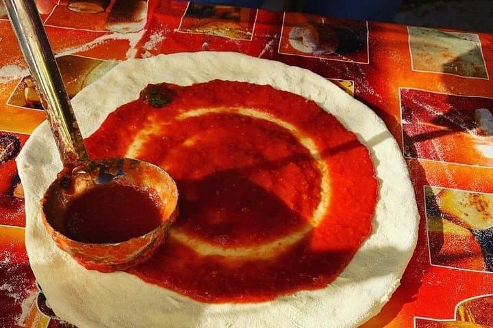 Covering the dough with tomato sauce
