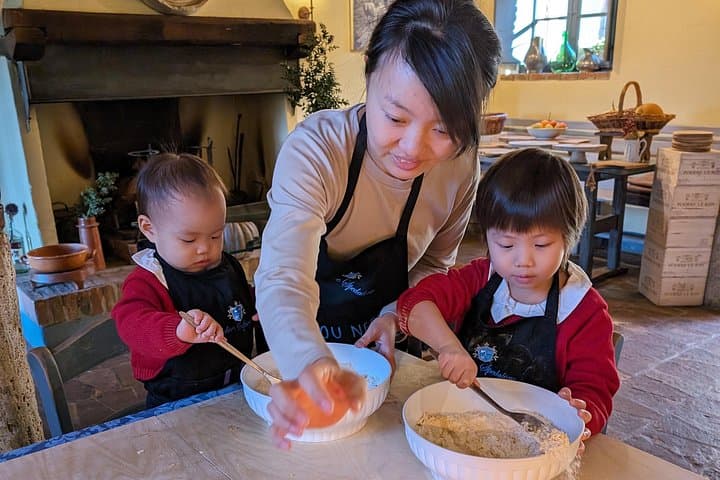 A family making pasta together at the tuscan cooking class of Podere Spedalone!