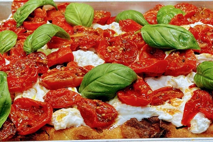 Focaccia with Tomatoes and Burrata: Savor this focaccia topped with sun-ripened tomatoes, creamy burrata cheese, and fresh basil, a perfect combination of textures and flavors.