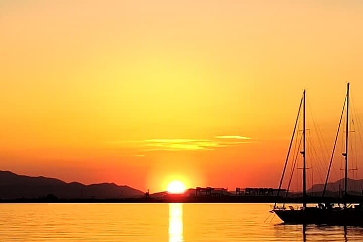 Flat sea, a sailboat passing by. Karel, in the name of Punic of the city of Cagliari