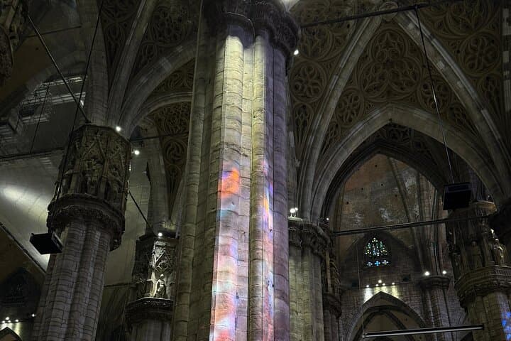 Colorful light from stained glass dances across the towering stone columns of a majestic Gothic cathedral