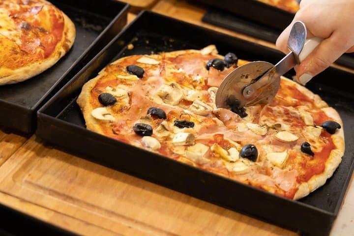 Slicing freshly baked pizza before tasting it.