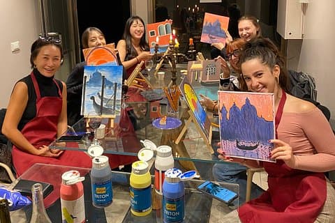 Guests proudly showing their finished paintings, guided by artist Cecilia, enjoying a creative and social evening