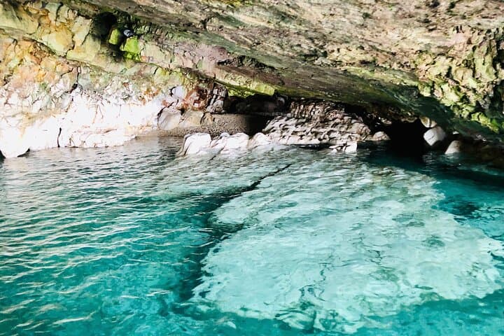 A hidden bay, surrounded by white stone cliffs, where the crystal clear sea fades to turquoise. Transparent waters invite swimming, while the sun shines
