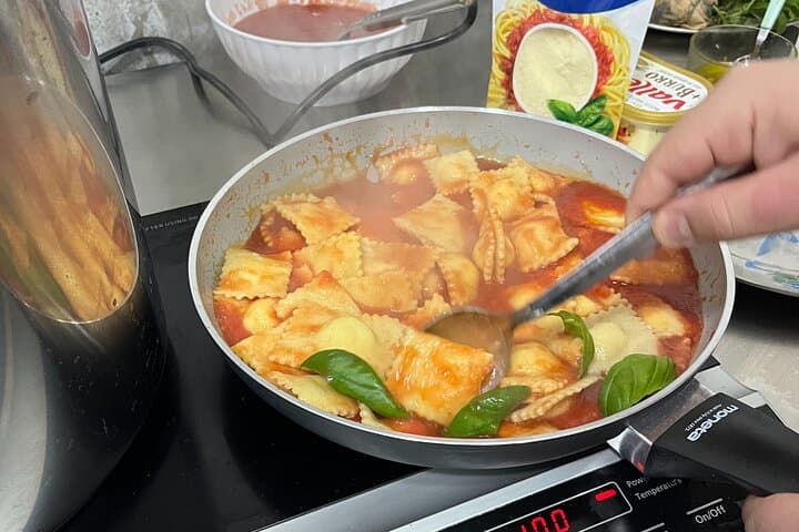 Mixing ravioli with tomato sauce.