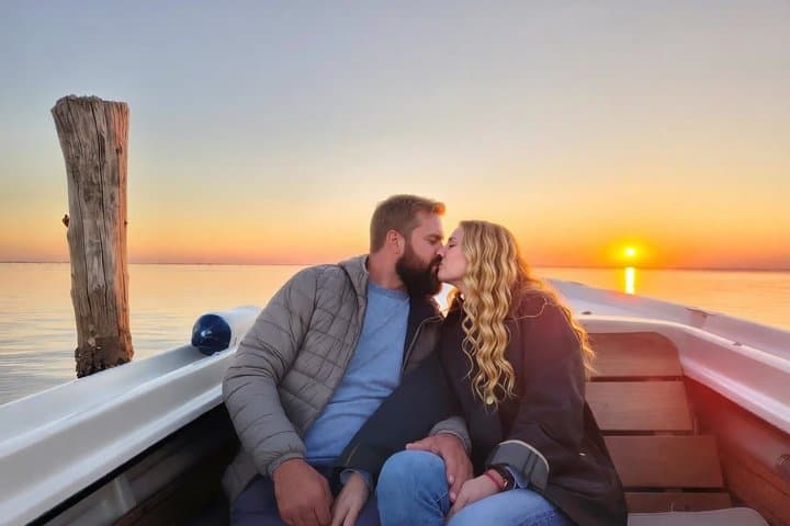 German couple in love kissing during sunset boat tour in the Venetian lagoon