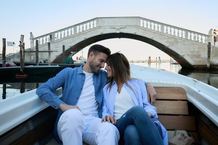 A couple in love under the Vigo Bridge in Chioggia during a boat tour.